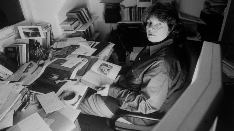 Prize-winning novelist A.S. Byatt working at cluttered desk in her study at home.