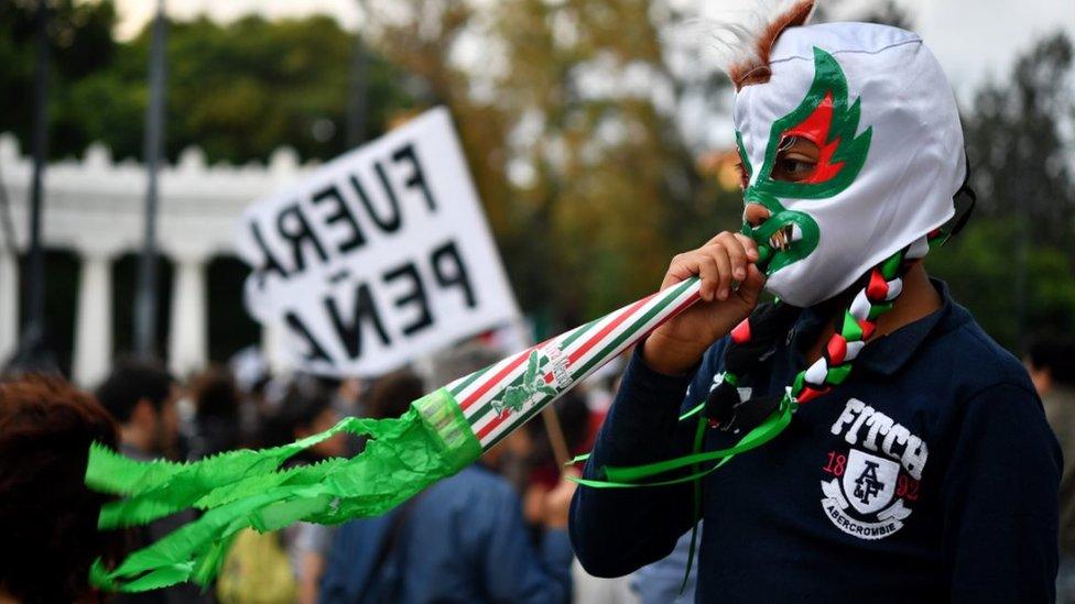 A boy in a mask watches the demonstration in Mexico City