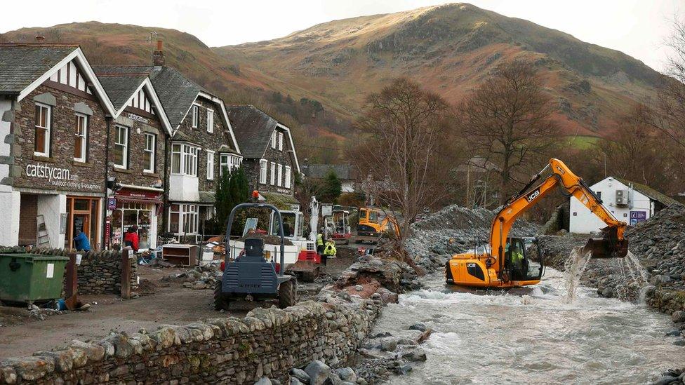 An excavator dredges the riverbed after it burst it's banks, flooding the village of Glenridding