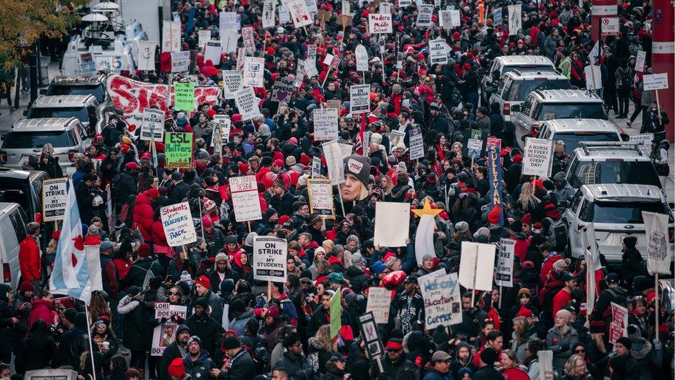 Huge crowd of people holding signs as they take to the streets