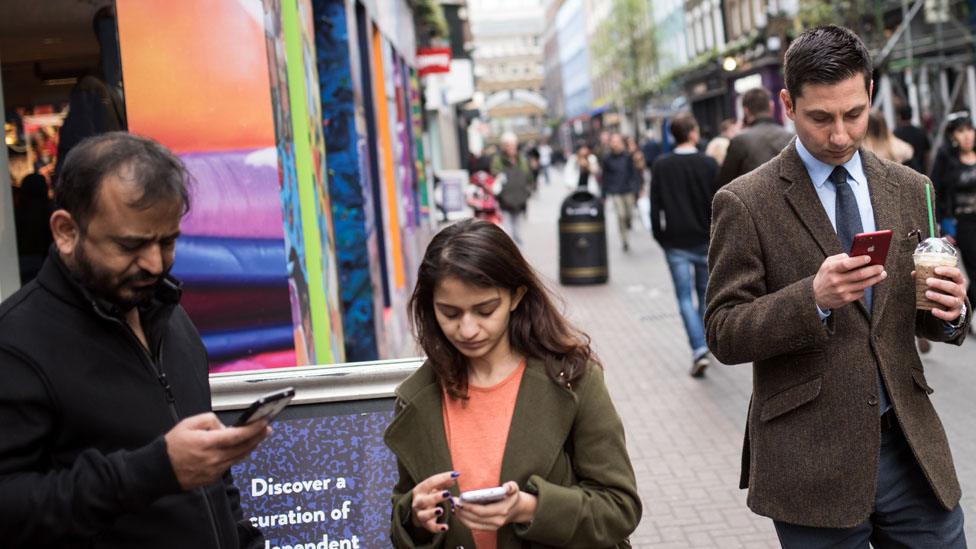 Shoppers look at their mobile phones