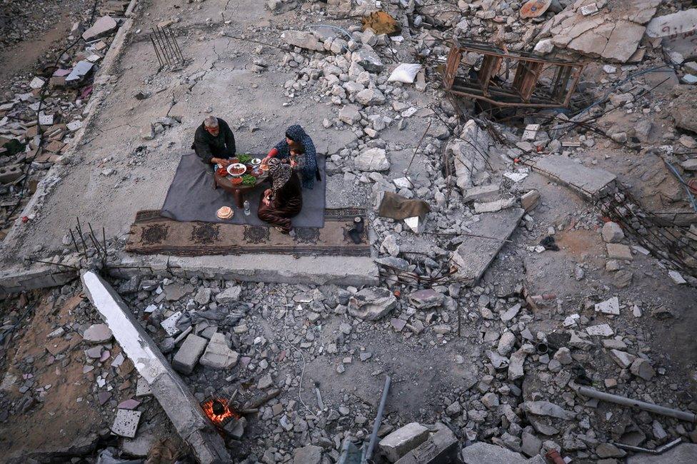 Khaled Naji and family share a meal in the ruins of his home in Gaza. "There is no joy in this Ramadan," he said. (Majdi Fathi/BBC)