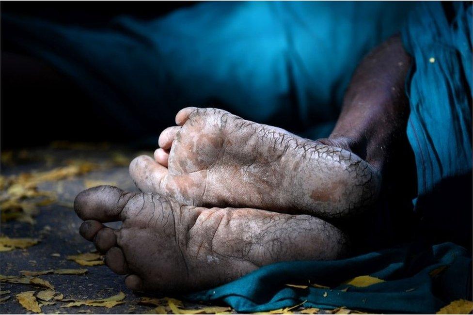 A shaft of light catches the weathered feet of an Indian farmer from the southern state of Tamil Nadu, as he sleeps on a foothpath during a protest in New Delhi on March 26, 2017.