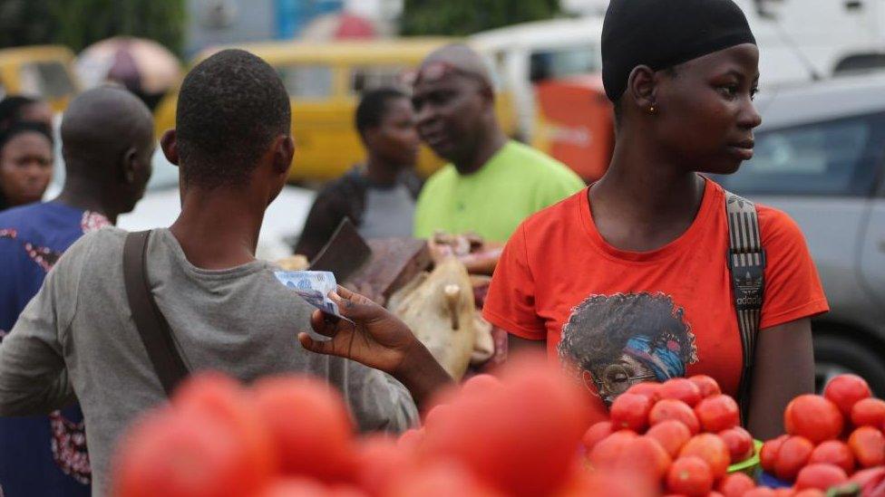 A woman holds new Nigerian naira notes in an open market in Lagos, Nigeria, 17 December 2022