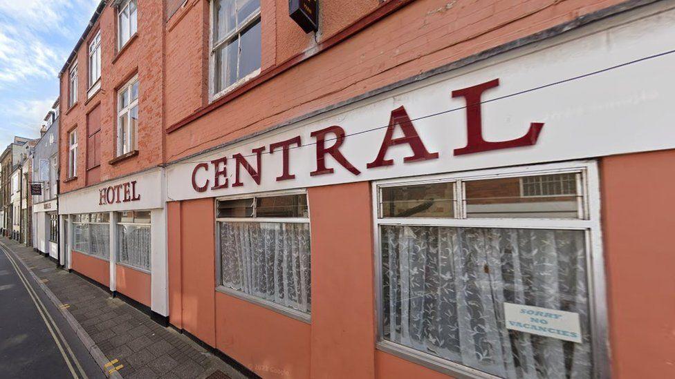 Hotel Central, a three-storey building spanning converted terrace properties in a residential street. The hotel is painted in an orange-brick colour and has a prominent name sign above ground floor windows.