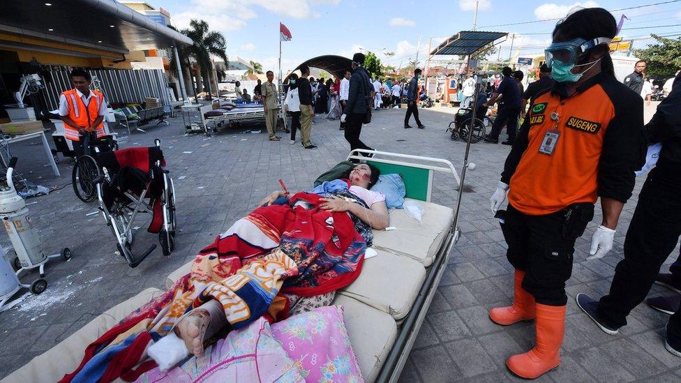 An injured quake victim waits for medical help outside the Moh. Ruslan hospital in Mataram on the Indonesian island of Lombok