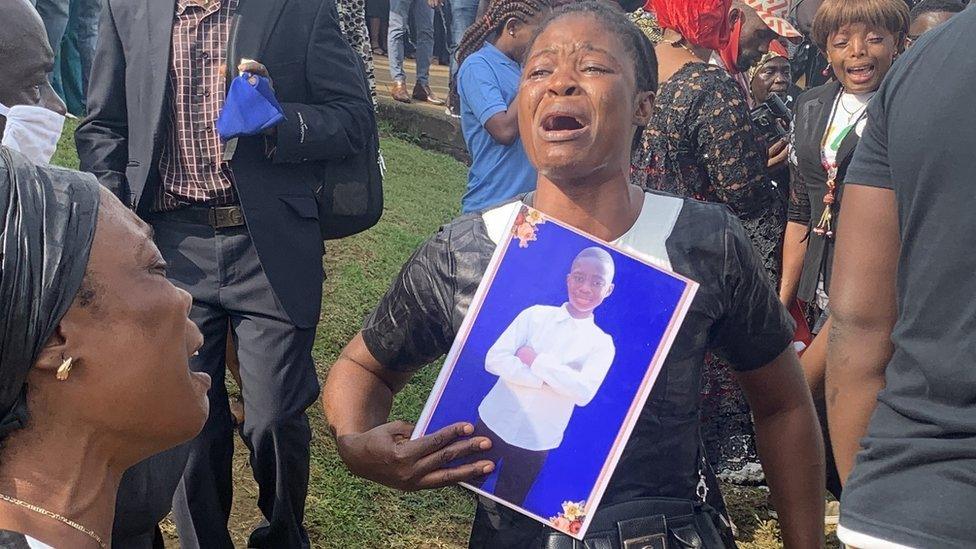 A mourner clutched a photo of one of the dead children