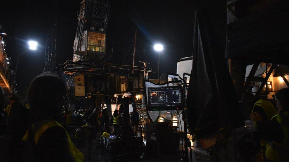 Image of the crew filming at night at Princes Wharf. Lots of people can be seen, as well as a monitor.