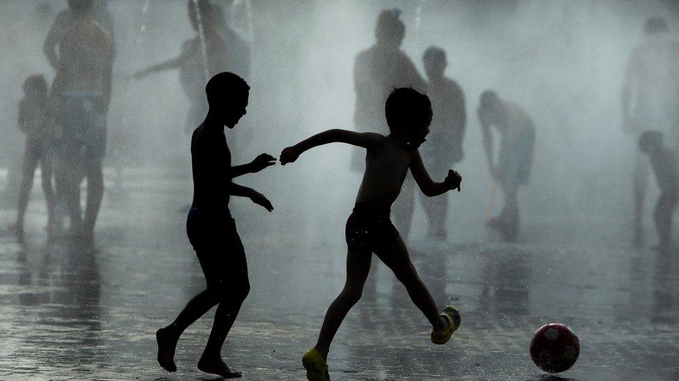 Children play soccer as they cool down in a fountain beside Manzanares river in Madrid, Spain, Monday, 29 June 2015.