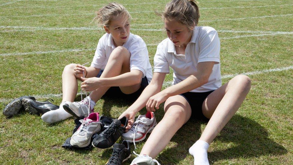 Girls lacing up football boots