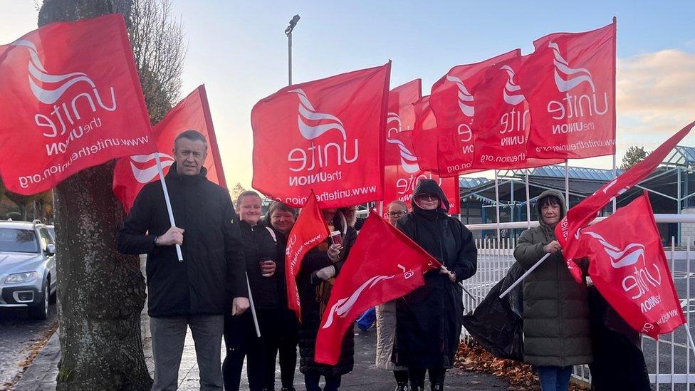 Unite the Union members hold red flags on the picket line at Glenveagh school in south Belfast