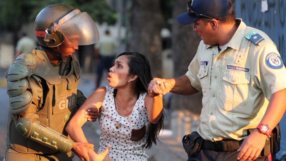 A woman is detained by security forces after looting broke out