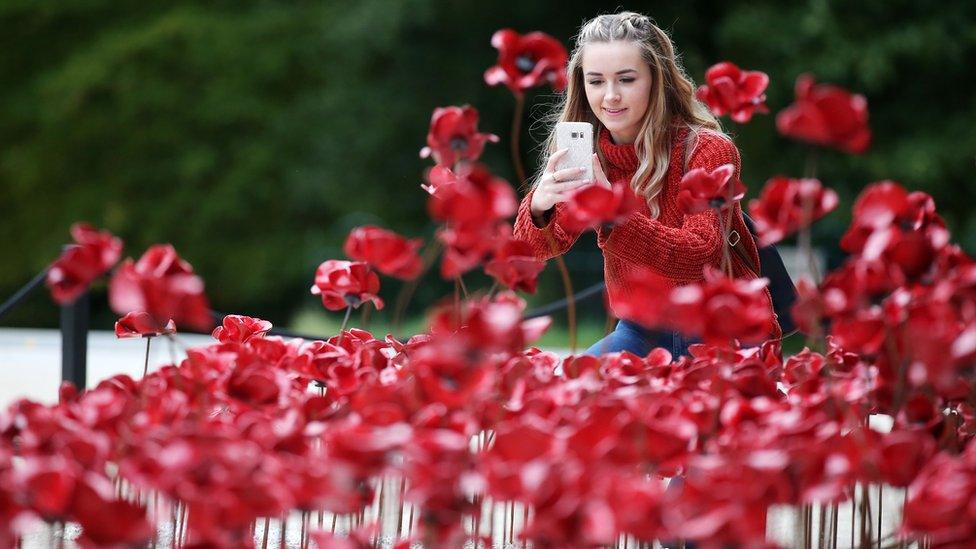 A girl takes a photo of the Weeping Window at the Ulster Museum