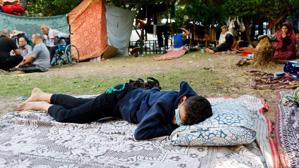 A boy sleeps in the open outside Shia hospital, which has become a refuge for Gazans