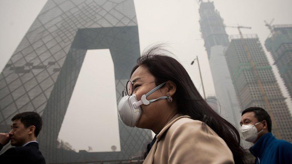 A woman wearing a protective pollution mask walks on a street in Beijing on March 20, 2017