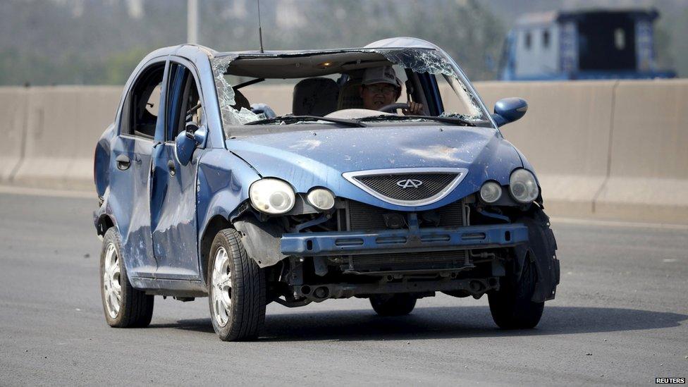 A driver is seen inside a damaged car on a highway near the site of the explosions at the Binhai new district in Tianjin August 13, 2015.