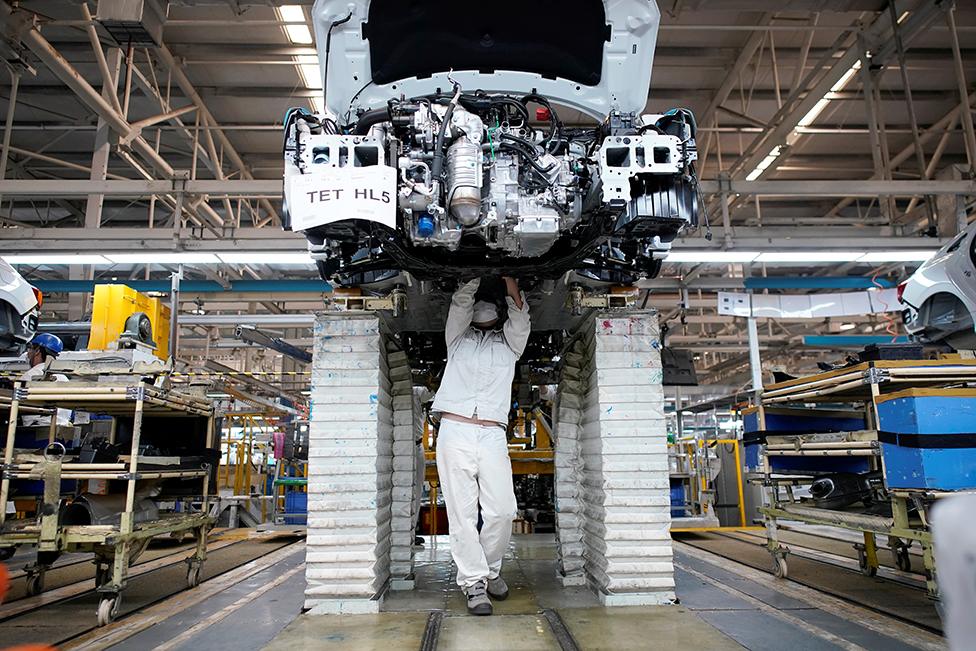 An employee works on a car production line