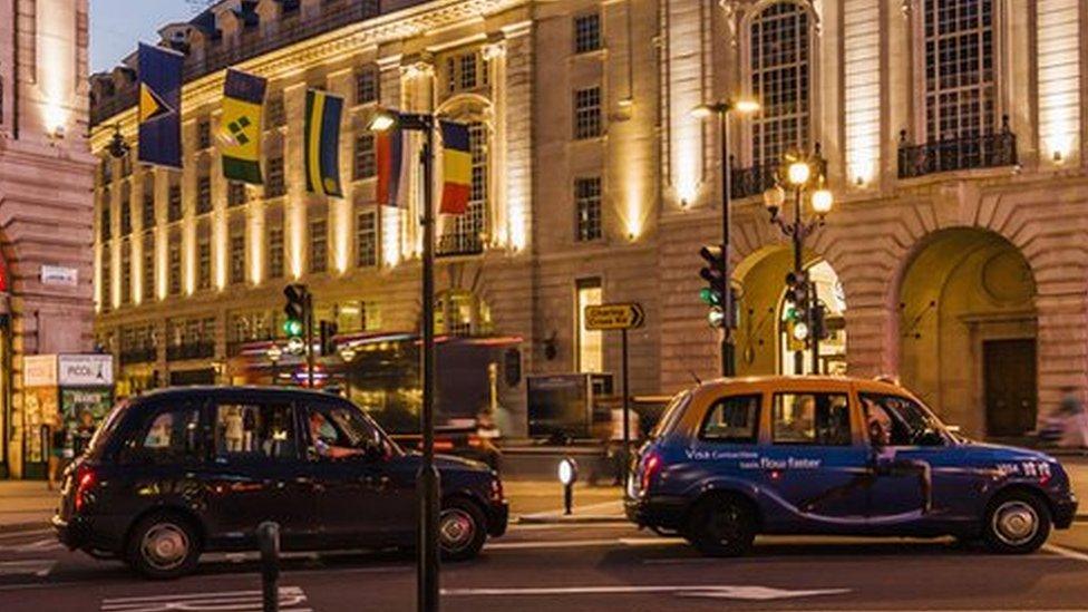 Two black cabs drive through Piccadilly