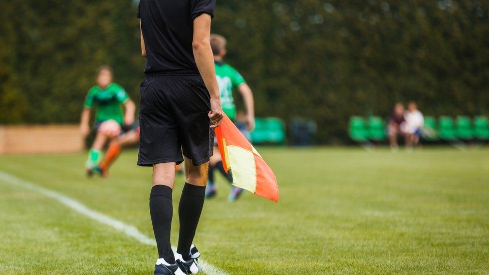 a referee holding the offside flag which signals an offside offence