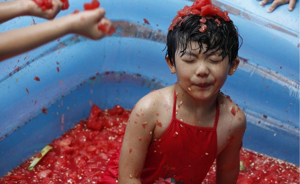 A child plays in watermelon flesh during a watermelon war activity in Hangzhou in July 2015