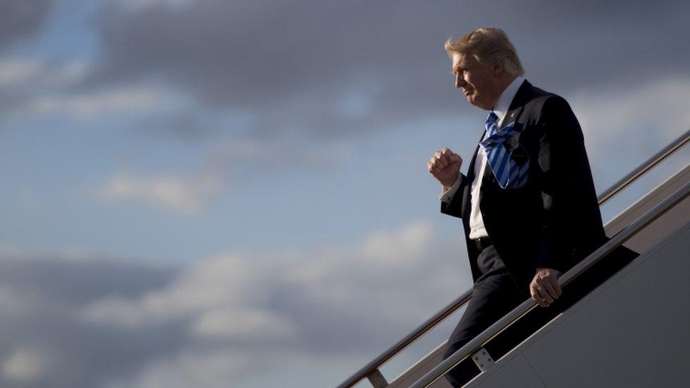 Trump walks down the steps of a plane