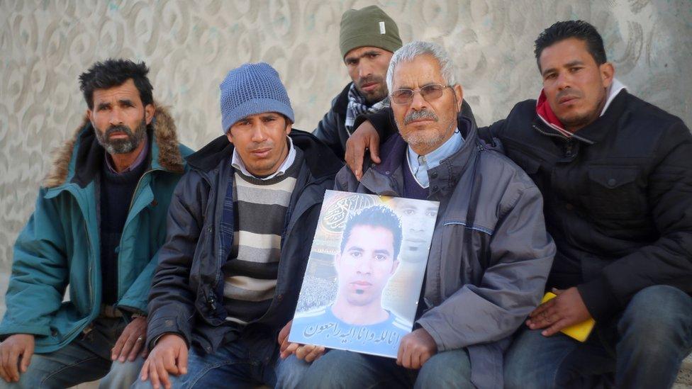 Othman Yahyaoui (C) poses with family members for a photo in the central Tunisian town of Kasserine on January 21, 2016, holding a portrait of his son, Ridha Yahyaoui