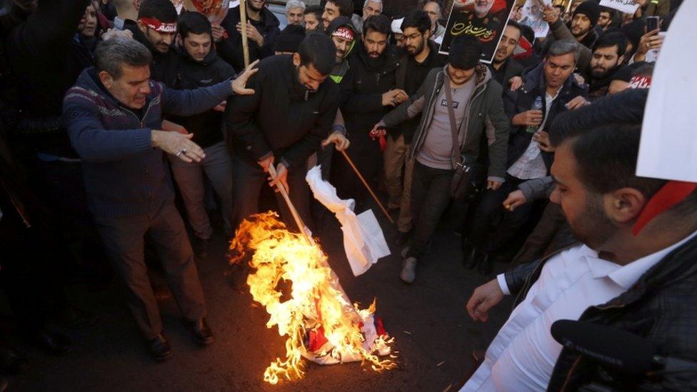 Protesters burn a UK and Israeli flag in Tehran