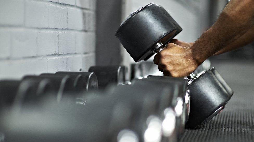 Male Picking Up Dumbbells in Gym