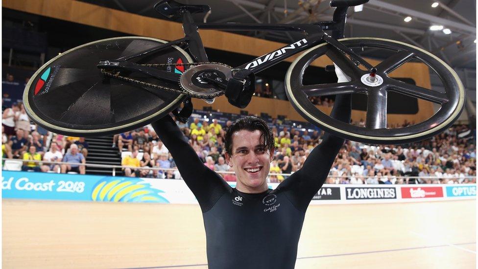 Sam Webster holds a bike above his head