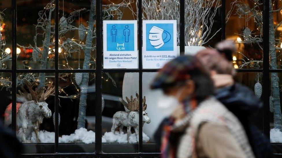 People pass by a restaurant window displaying coronavirus disease (COVID-19) safety measures,