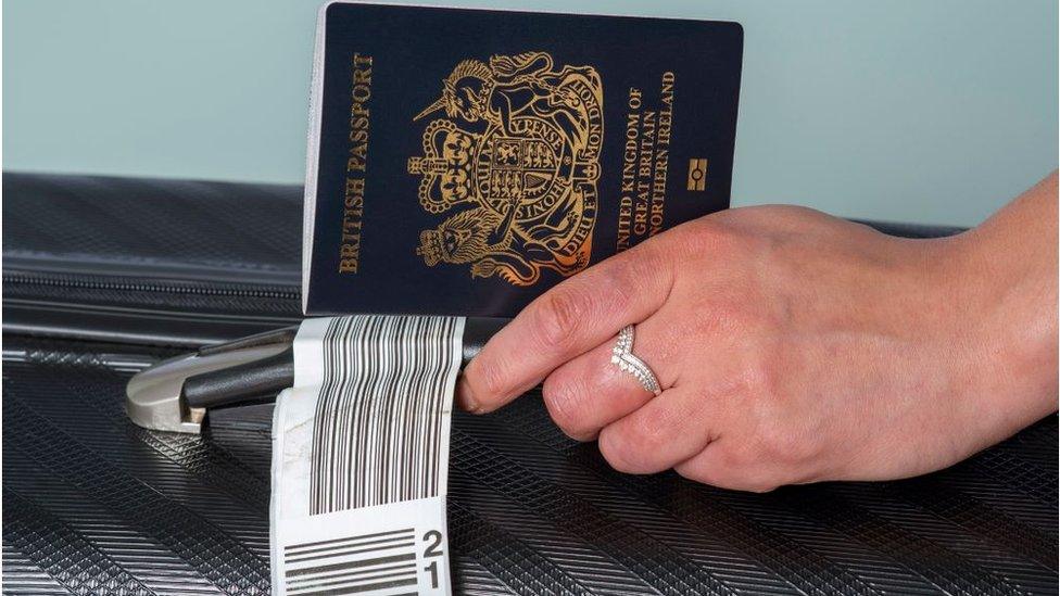 Woman holding a passport by her suitcase