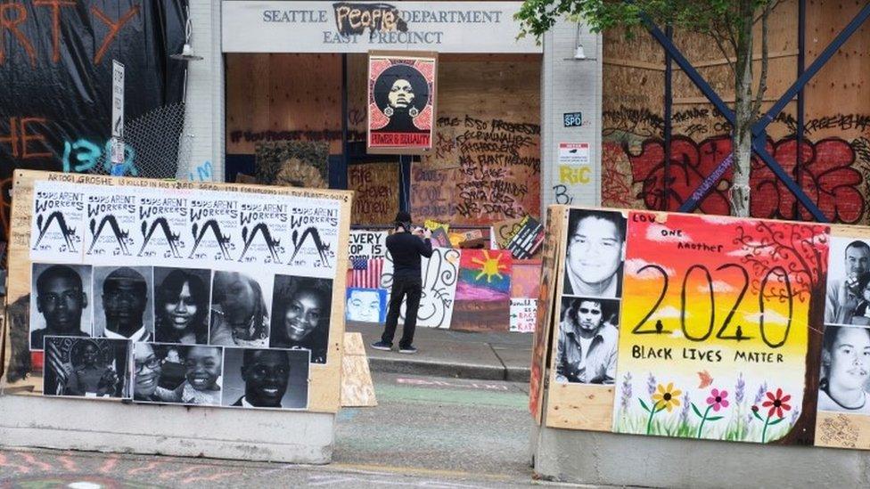 A man takes a picture outside a police station, abandoned by police, in the Capitol Hill neighbourhood