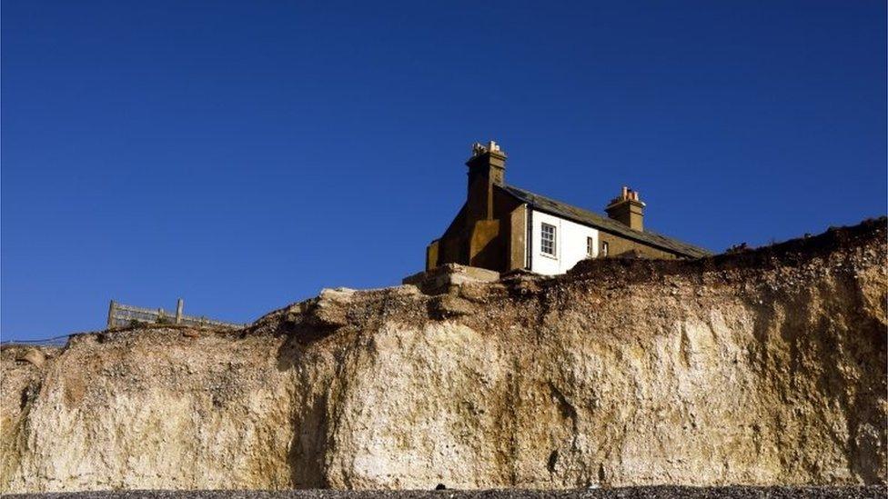 Row of cottages near an eroding cliff edge at Birling Gap and the Seven Sisters, East Sussex