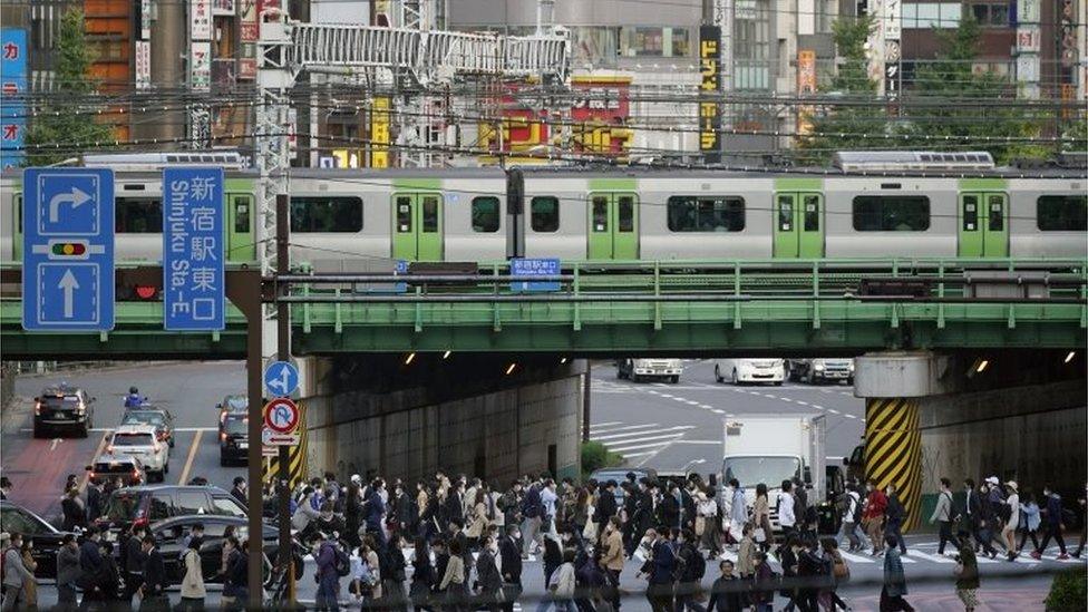 Pedestrians cross a street at Shinjuku commercial, business and administrative centre in Tokyo, Japan, 18 November 2020.