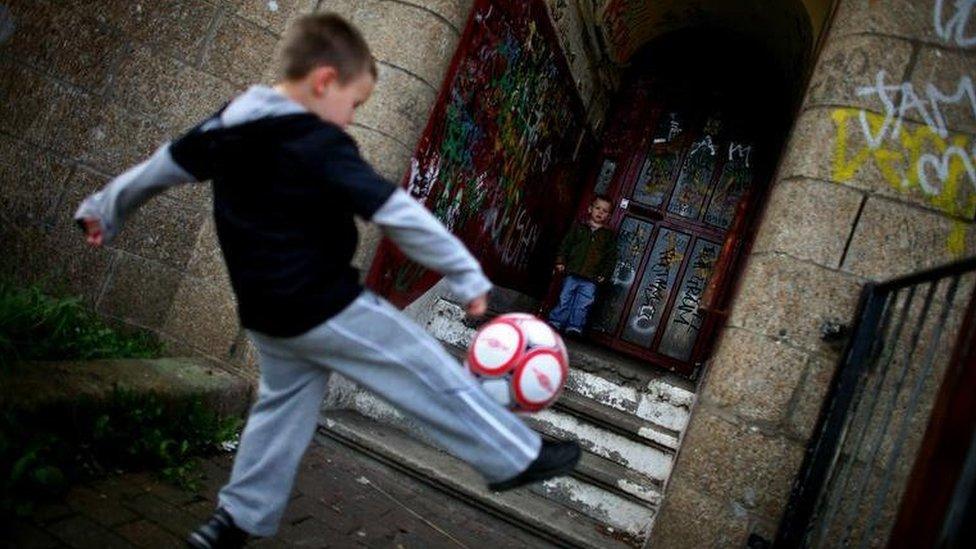 Boys playing football in a derelict building