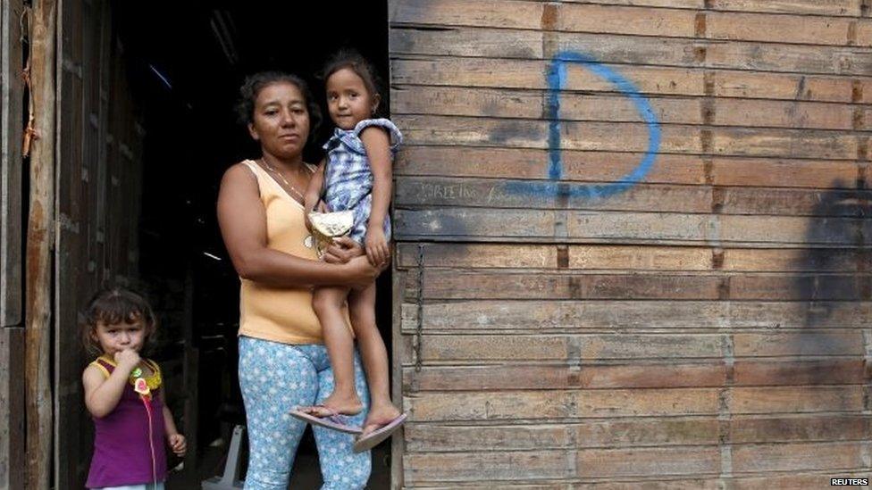 A woman and her daughters pose for a picture at the door of her house, which was marked for demolition with the letter D, in San Antonio in Tachira state on 25 August, 2015.