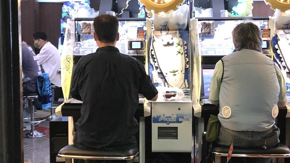 A man wearing a cooling vest inside a Tokyo arcade