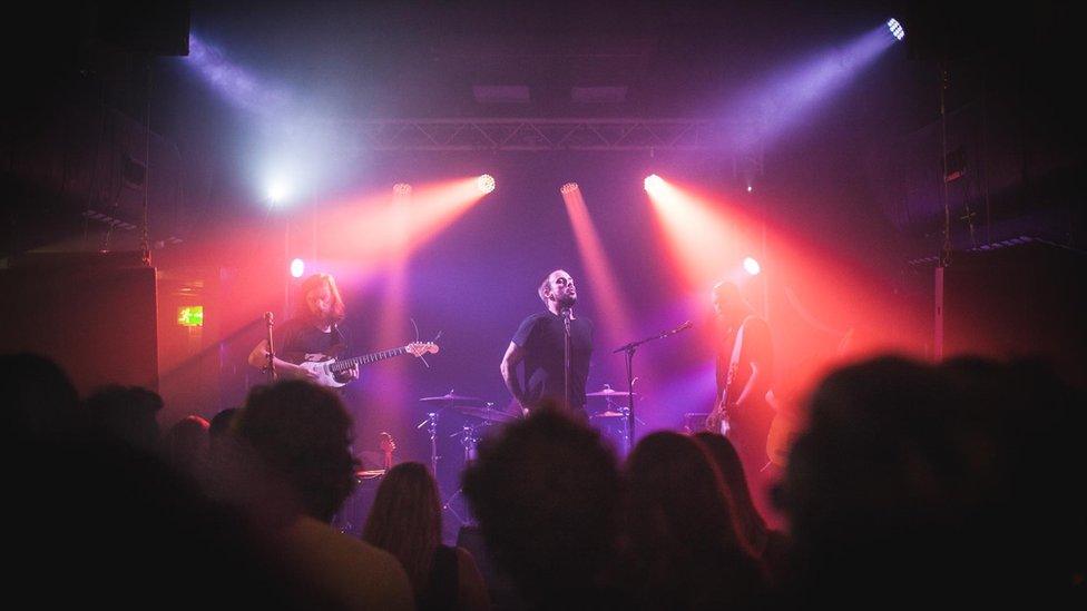 Idles performing onstage in Thekla under pink and red lighting