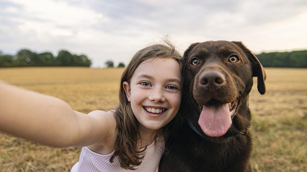 Girl taking selfie with dog