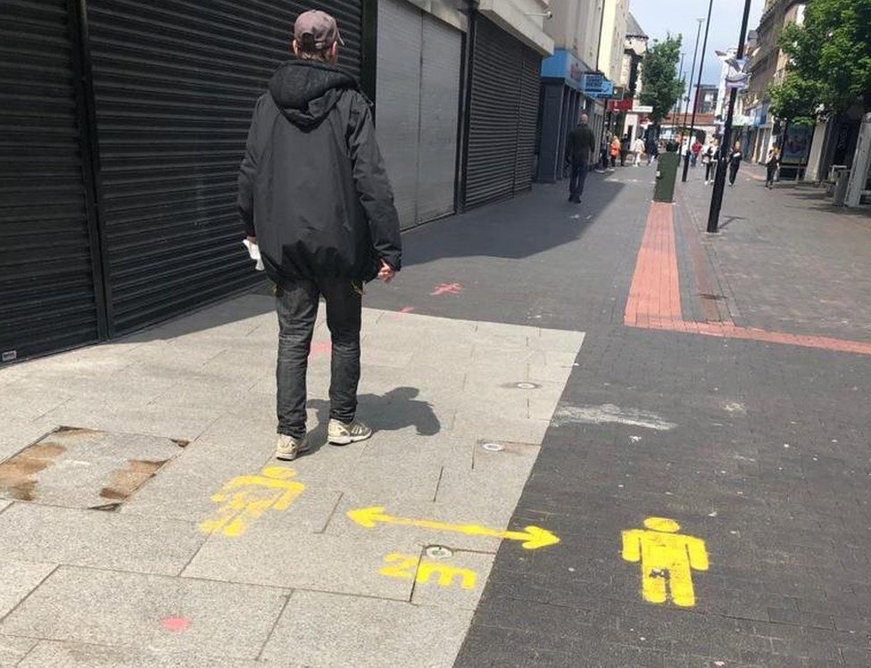 Man walking in Middlesbrough with social distancing sign