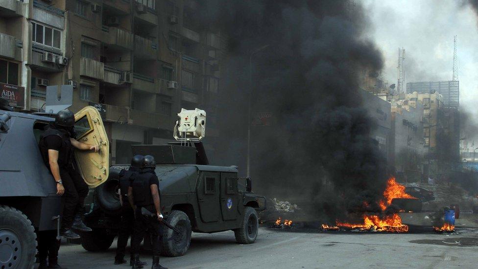 Armoured vehicles approach a flaming barrier in Cairo on 14 August 2013