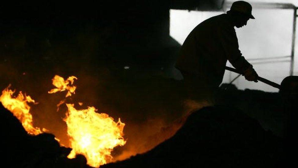 A steelworker stirs material next to a steel making furnace at the Chongqing Iron and Steel Factory in Chongqing Municipality, China