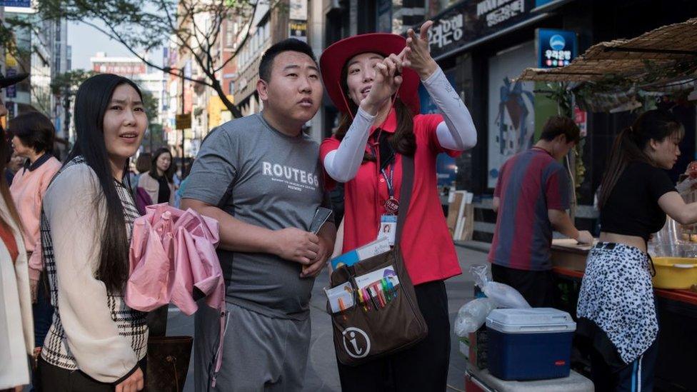 South Korean tour guide giving directions to Chinese tourists