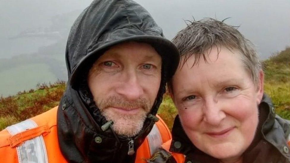 A man and woman smile at the camera in the rain