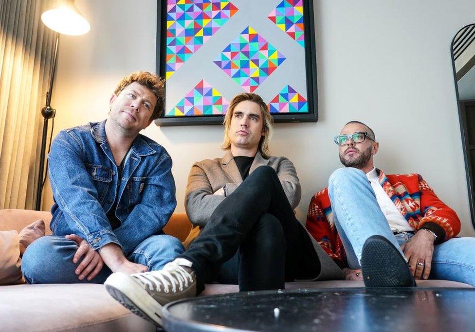 Busted musicians James Bourne, Charlie Simpson and Matt Willis sitting on a couch