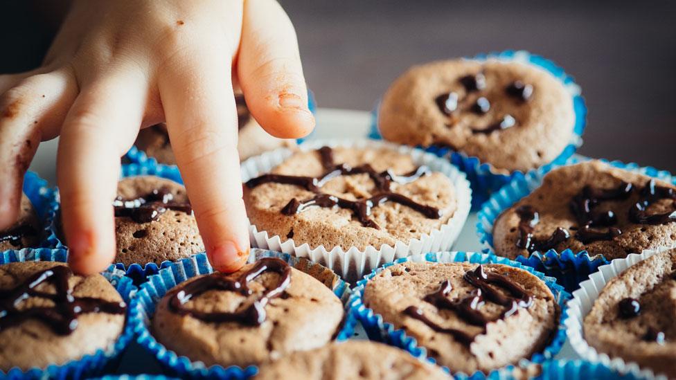 Child reaching for a cake