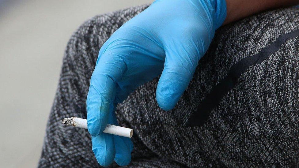 Woman's gloved hand holding cigarette