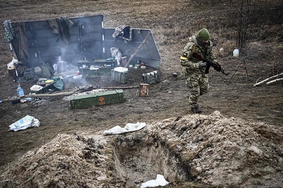 A Ukrainian soldier walks by a campfire north-east of Kyiv on 3 March 2022