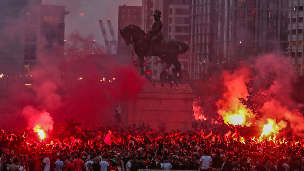 Flares lit around statue