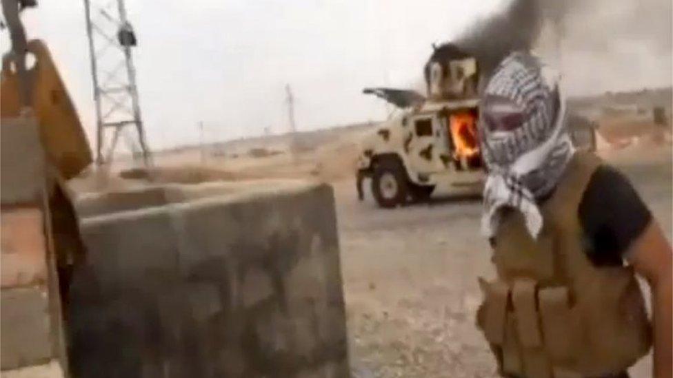 IS militant next to burning Iraqi army Humvee in Tikrit (June 2014)